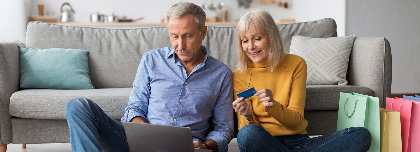 Couple sitting by couch shopping online 1600x580