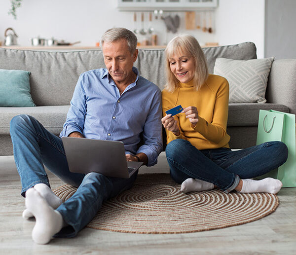 Couple sitting by couch shopping online 650x520